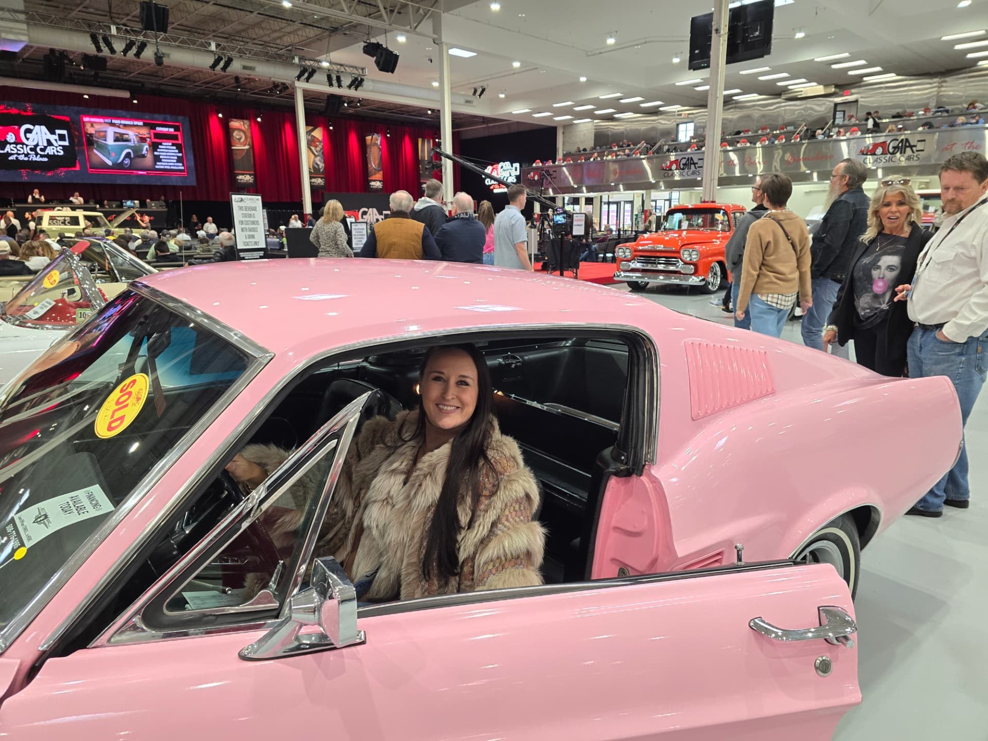 Nikki smiling from the driver's seat of Reba Lou at the auction, a SOLD sticker on the windshield.