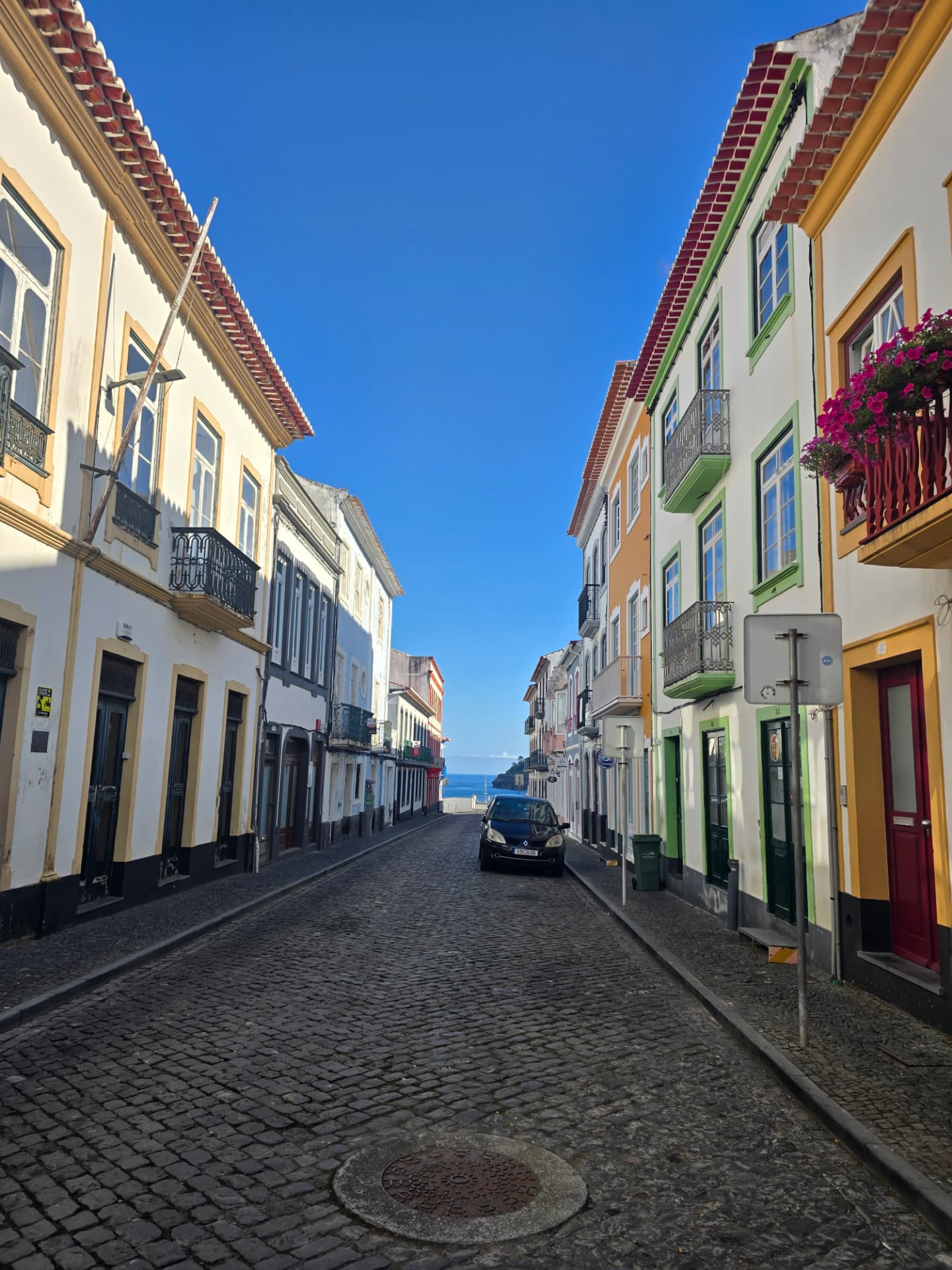 A cobblestone street of colorful houses running down to the sea in Angra.
