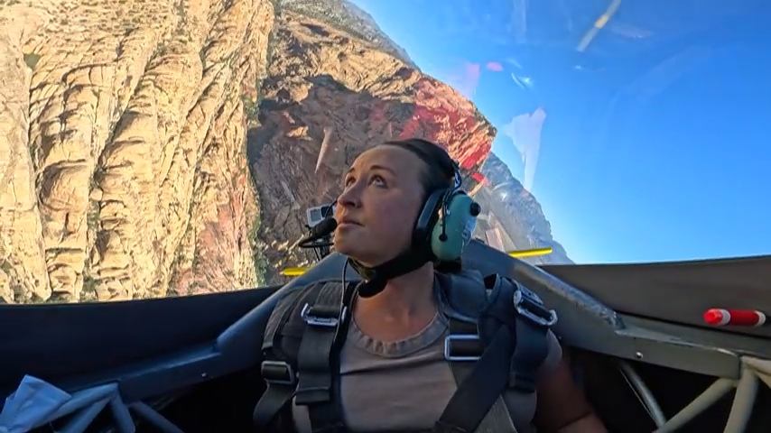 Nikki upside down in an aerobatic cockpit over red canyon walls.