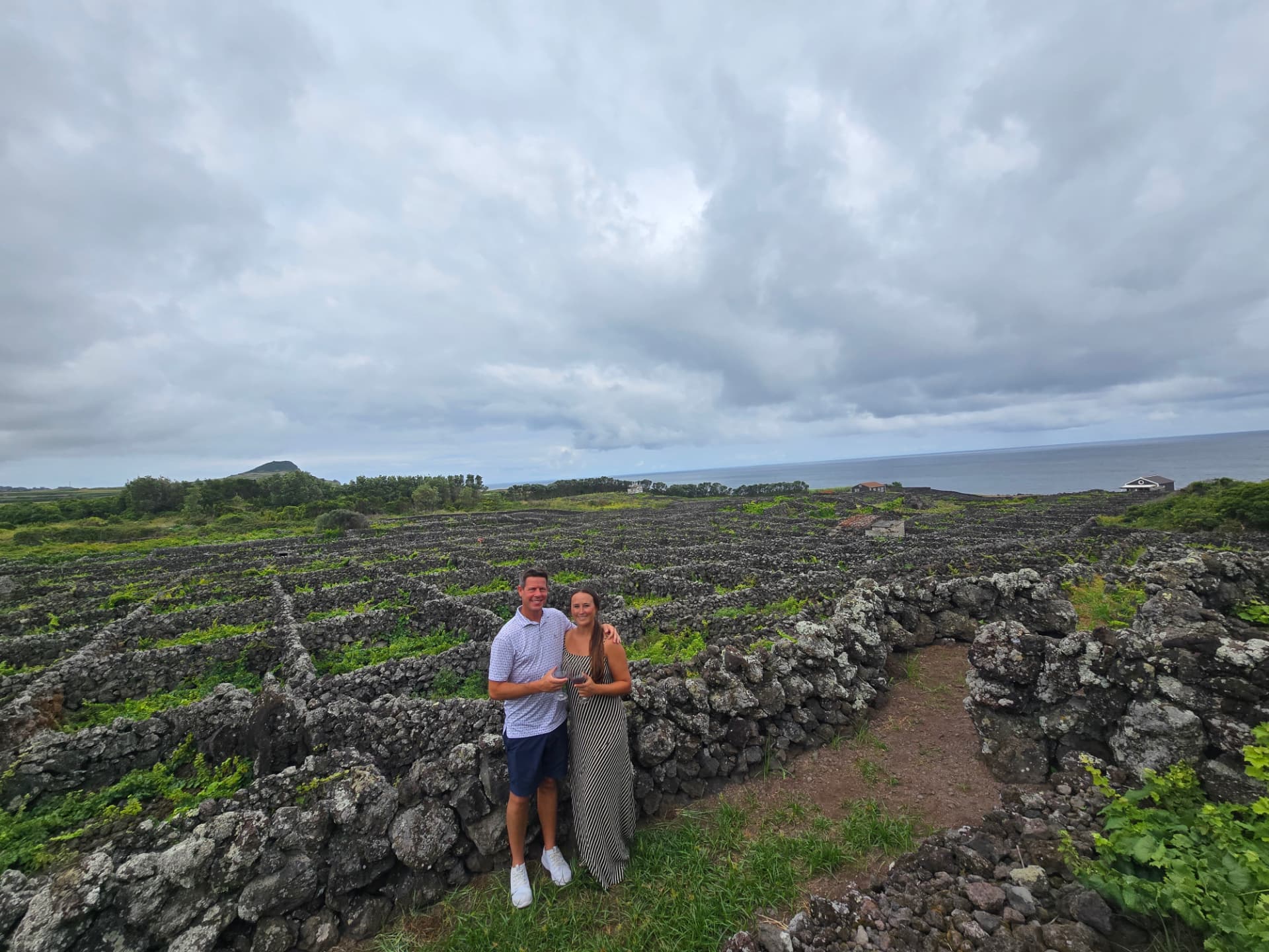 Nikki and Q with glasses of wine in the stone-walled vineyards of Biscoitos.