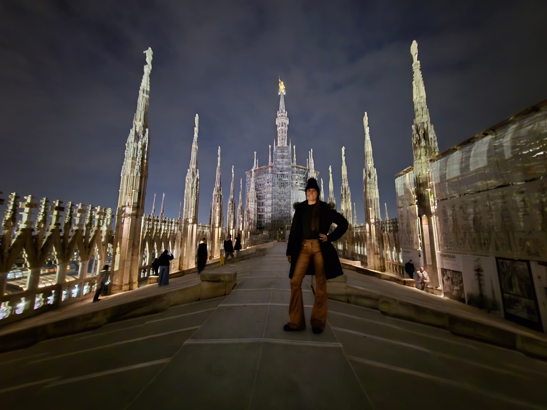 Nikki Bodie standing among the white marble spires on the roof of the Duomo di Milano at night.
